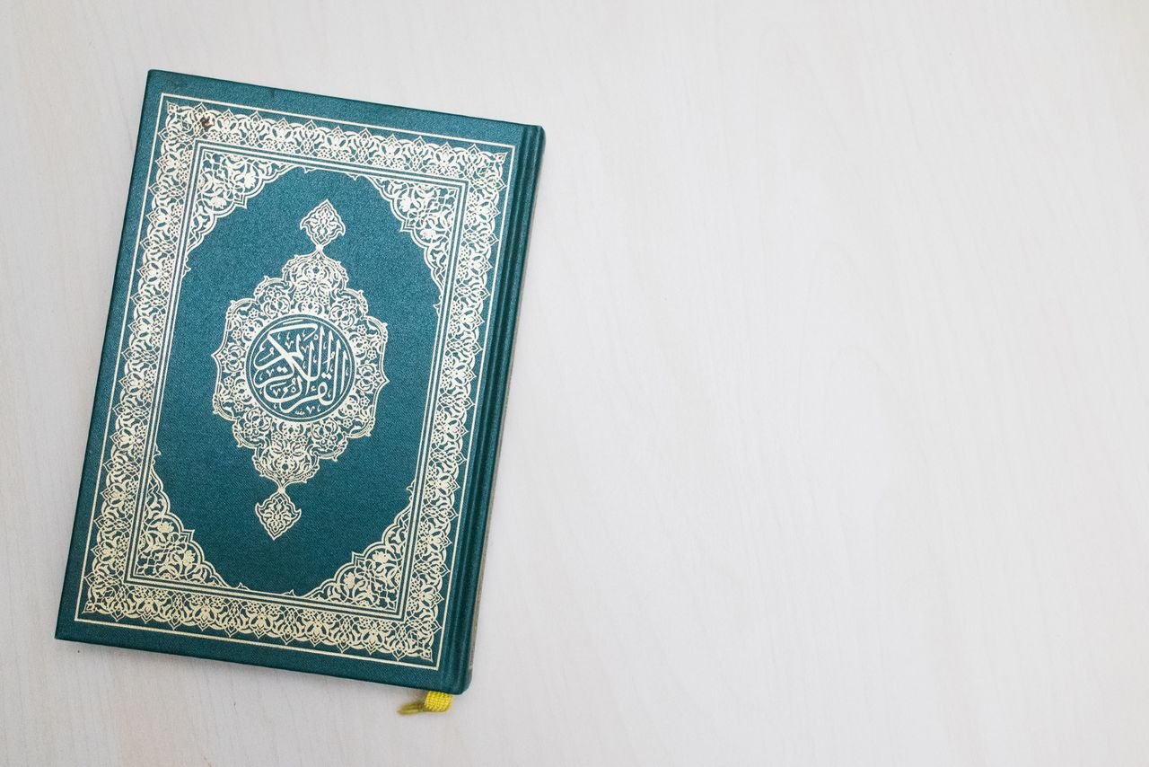 A Quran with intricate Arabic design placed on a white surface, highlighting its spiritual essence.