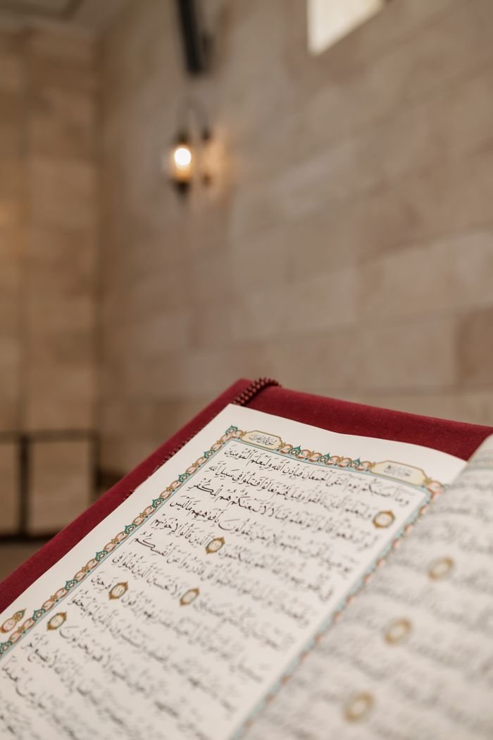 Close-up of an open Quran with intricate Arabic calligraphy in a mosque setting, highlighting Muslim culture.