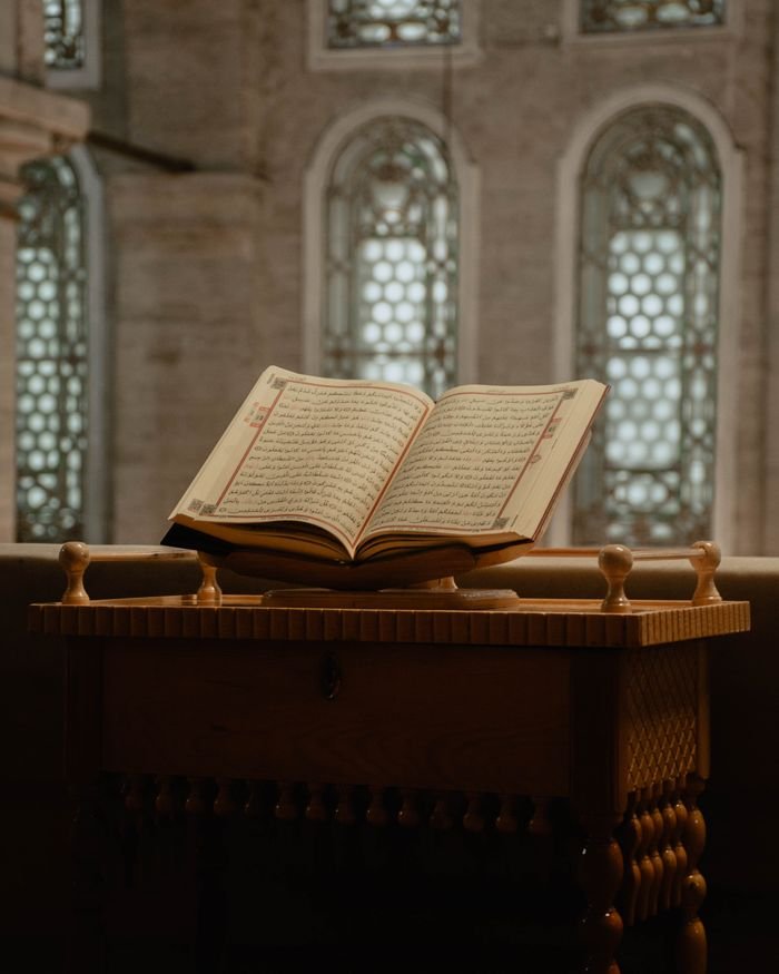 Open Quran on a decorative wooden stand within a mosque, showcasing spiritual ambiance.
